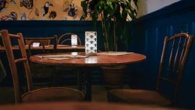 An empty round table with chairs pushed in, in a quiet restaurant